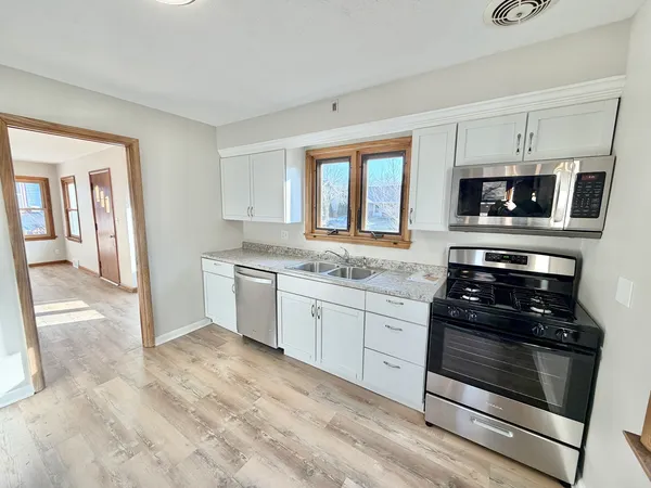 a kitchen with granite countertop a stove top oven microwave and cabinets