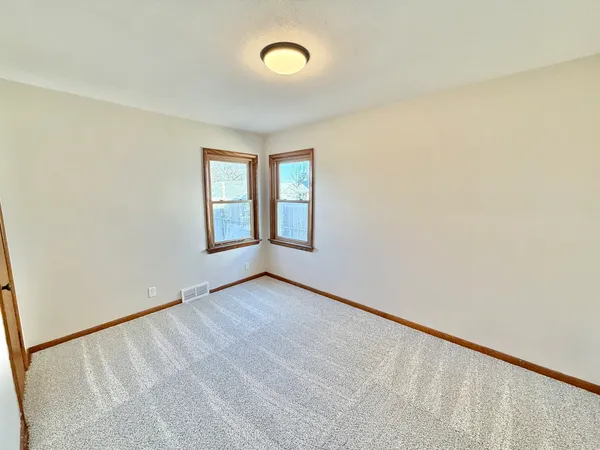 an empty room with windows & cabinet