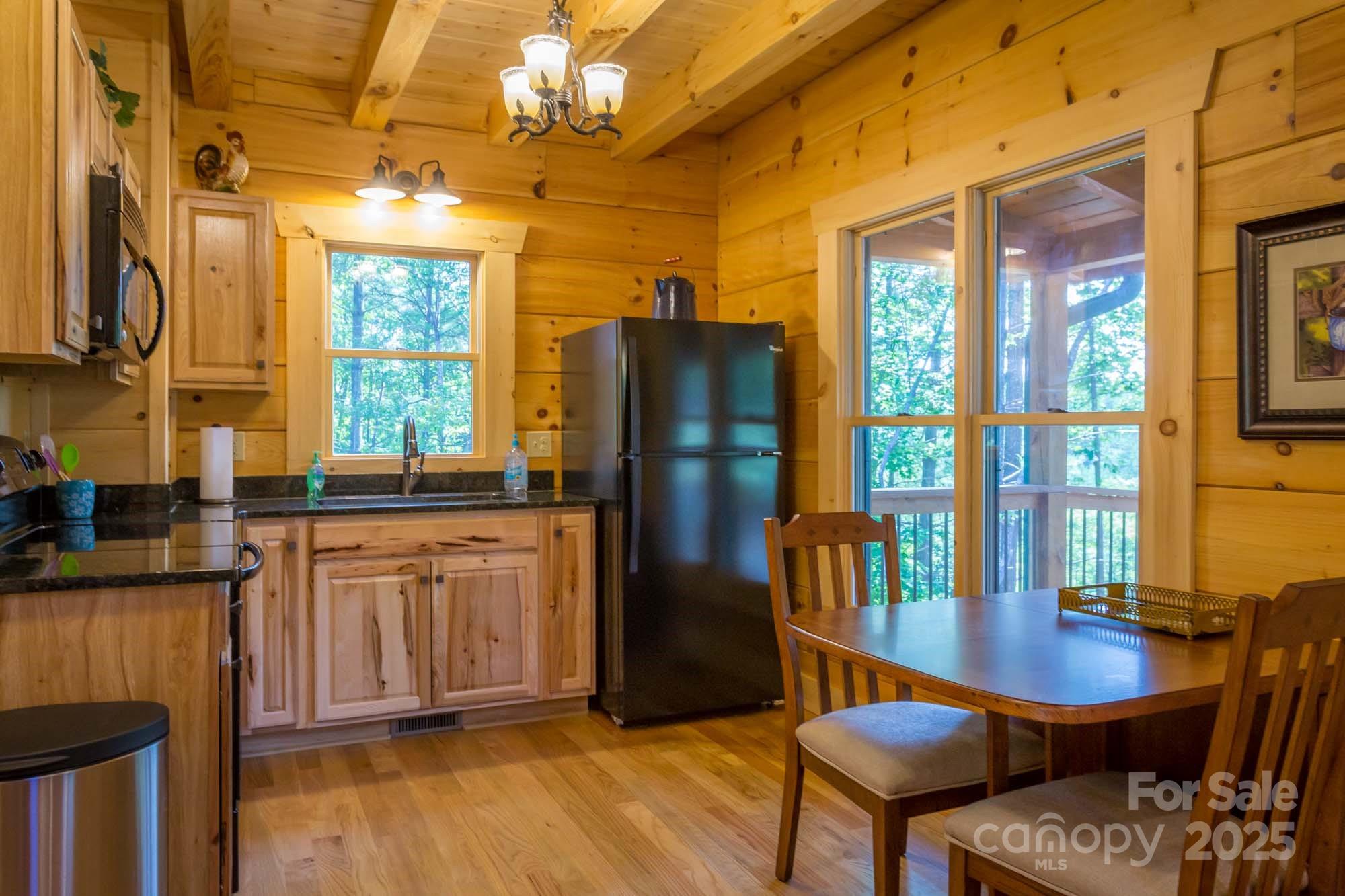 9587 Shortoff View Terrace, Unit 57 Nebo, NC 28761 - Photo 14 of 16 a kitchen with stainless steel appliances granite countertop a refrigerator a stove a dining table and chairs with wooden floor