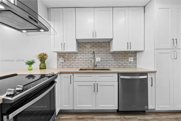 a kitchen with granite countertop a sink stainless steel appliances and white cabinets