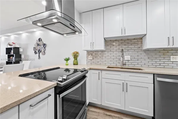 a kitchen with stainless steel appliances granite countertop a sink a stove and cabinets