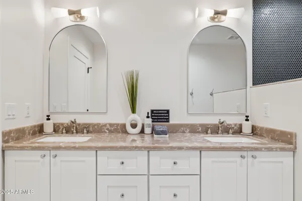 a bathroom with a granite countertop double vanity sink and mirror