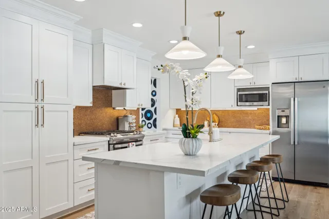 a kitchen with stainless steel appliances a sink a stove a refrigerator a dining table and chairs with wooden floor