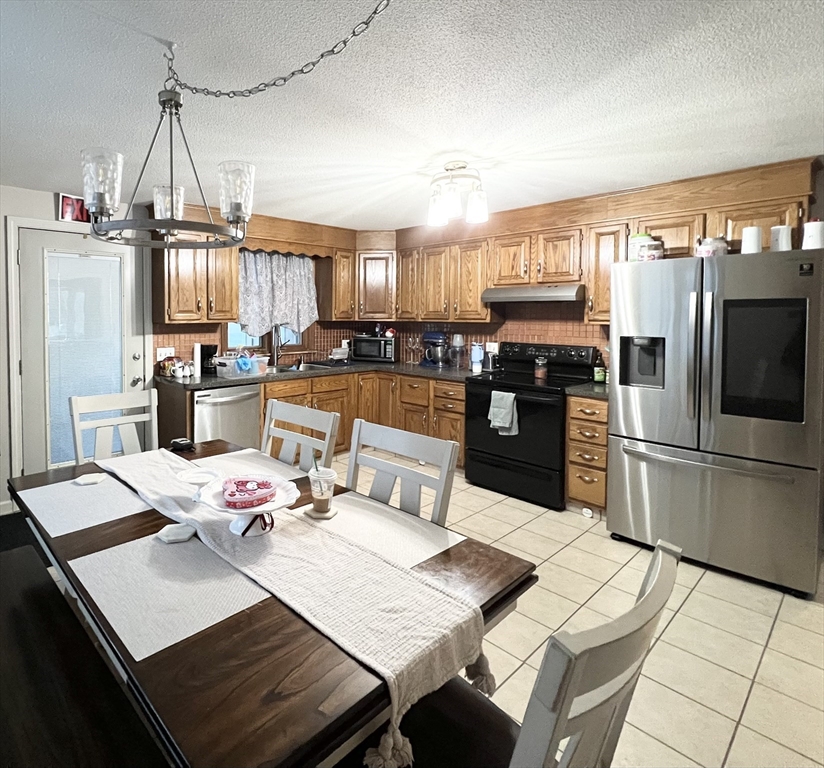 107 Enfield Street Springfield, MA 01151 - Photo 5 of 20 a kitchen with stainless steel appliances kitchen island granite countertop a refrigerator a stove a sink a dining table and chairs