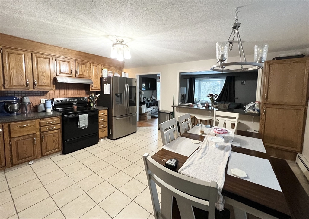 107 Enfield Street Springfield, MA 01151 - Photo 6 of 20 a kitchen with a refrigerator a stove a sink dishwasher a dining table and chairs with wooden floor