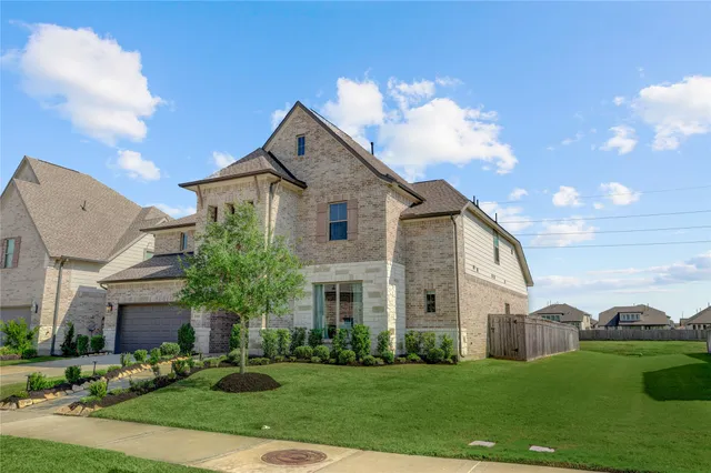 a view of a white house next to a yard with big trees