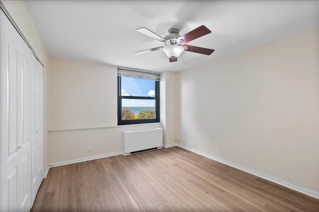 an empty room with wooden floor fan and windows