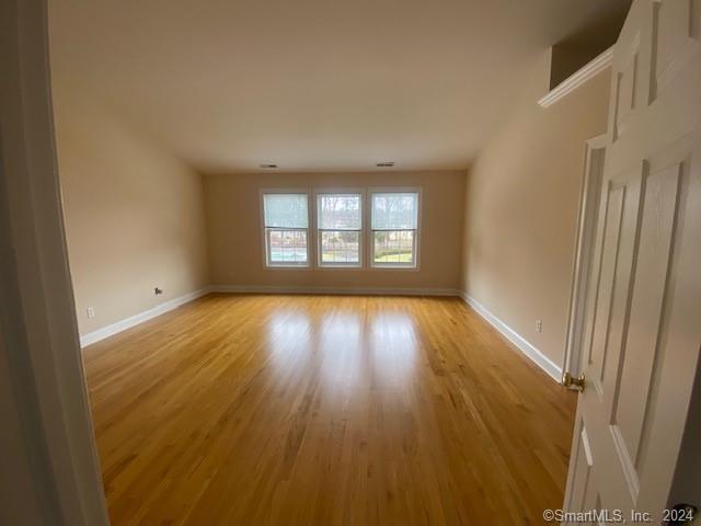 105 Lantern Court, Unit 105 Clinton, CT 06413 - Photo 3 of 6 an empty room with wooden floor and windows