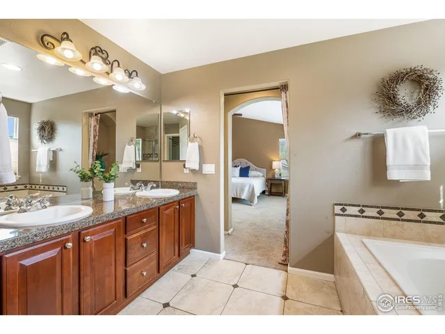 a spacious bathroom with a granite countertop sink a mirror and a bathtub