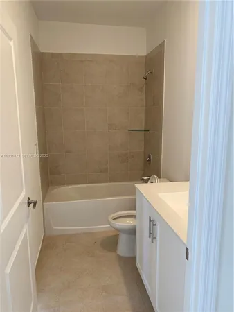 a bathroom with a granite countertop bathtub shower sink vanity and toilet