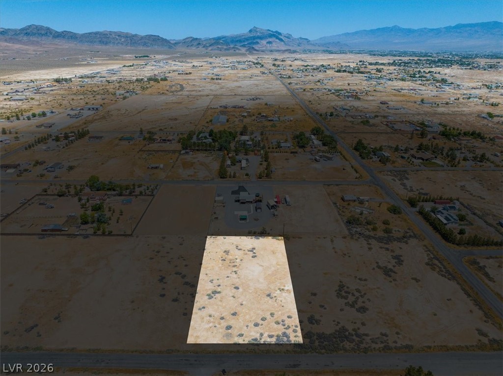4580 Lawrence Road Pahrump, NV 89048 - Photo 32 of 40 An aerial panorama reveals a vast, level desert lot primed for development, set against distant mountains.