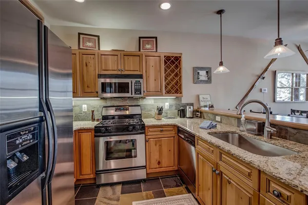 a kitchen with granite countertop a sink stainless steel appliances and cabinets