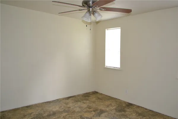 an empty room with a window and a fan