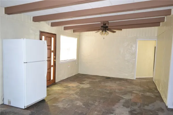 a view of a refrigerator in kitchen and an empty room