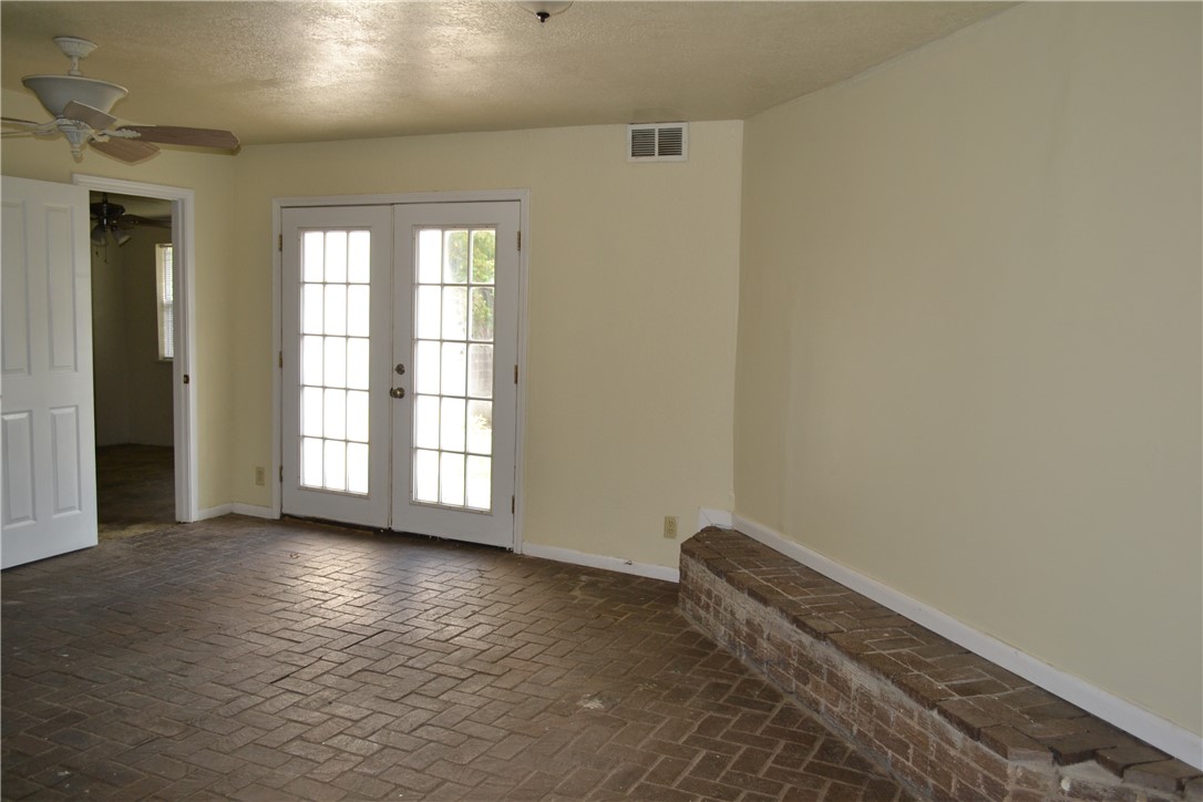 505 Foch Street Bryan, TX 77801 - Photo 4 of 17 Empty room featuring brick floors, a textured ceiling, french doors, and a ceiling fan