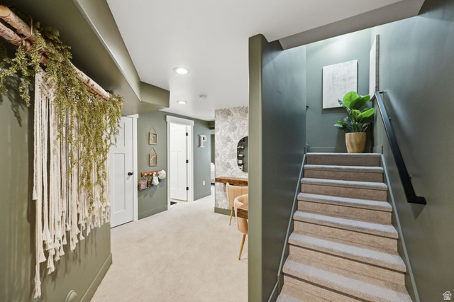 57 McCall Ln. Farmington, UT 84025 - Photo 25 of 36 Carpeted staircase with black metal handrail leading to a hallway with recessed lighting