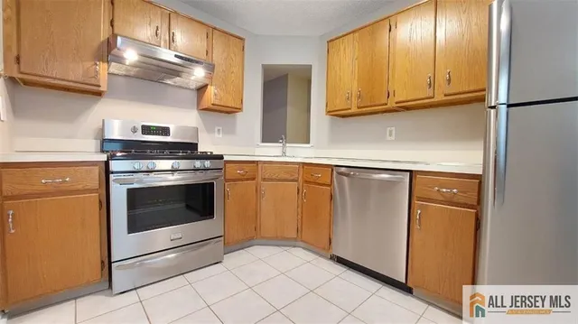 a kitchen with stainless steel appliances granite countertop a stove a sink and a refrigerator with cabinets