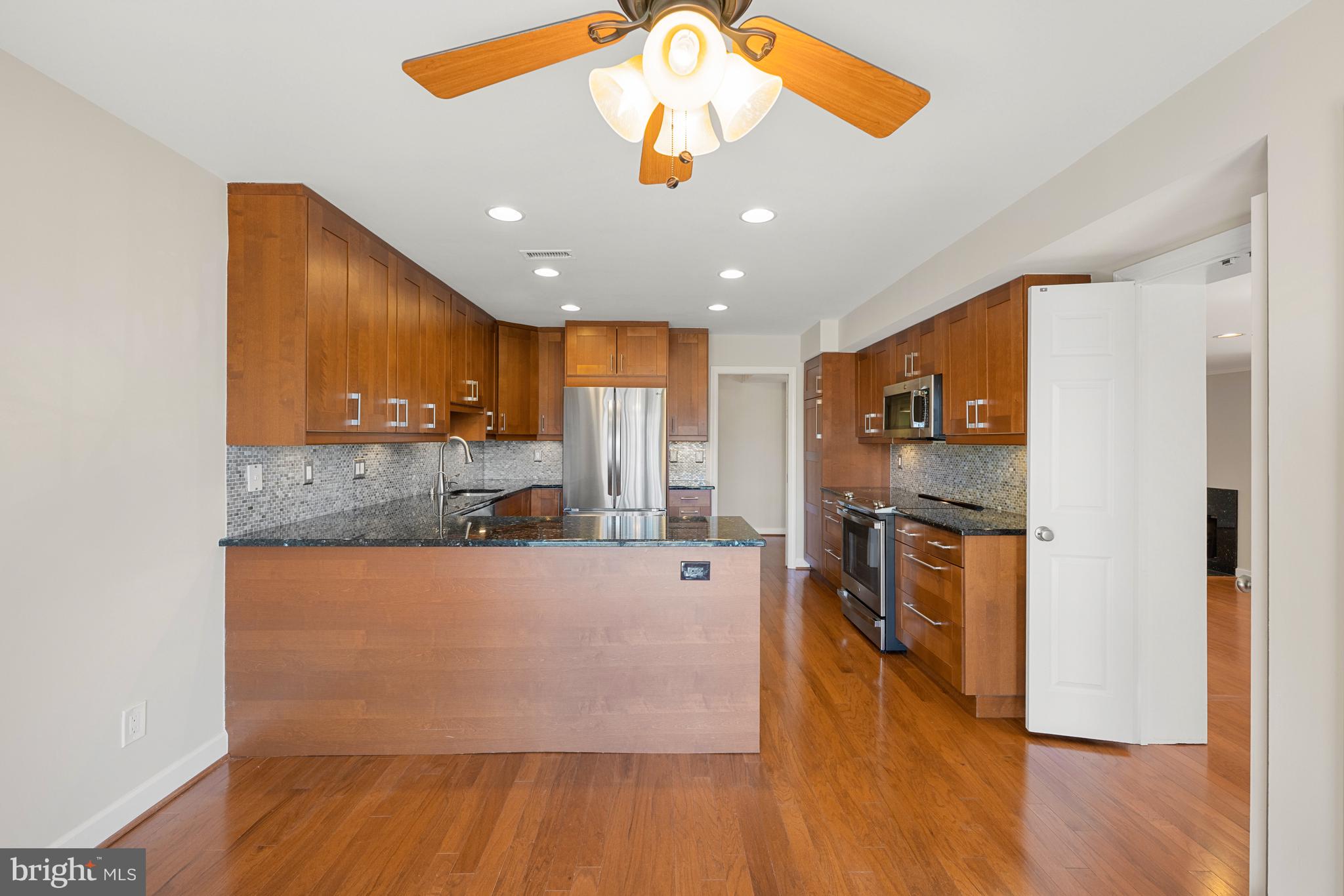 11400 Strand Drive, Unit R310 Rockville, MD 20852 - Photo 12 of 35 a large kitchen with stainless steel appliances granite countertop a refrigerator a stove and a wooden floor