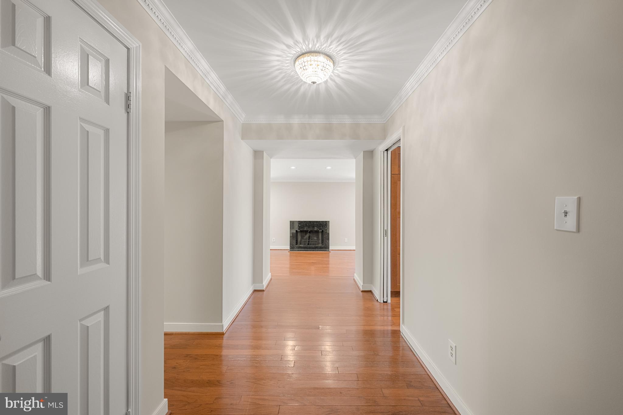 11400 Strand Drive, Unit R310 Rockville, MD 20852 - Photo 4 of 35 a view of a hallway with wooden floor and a chandelier