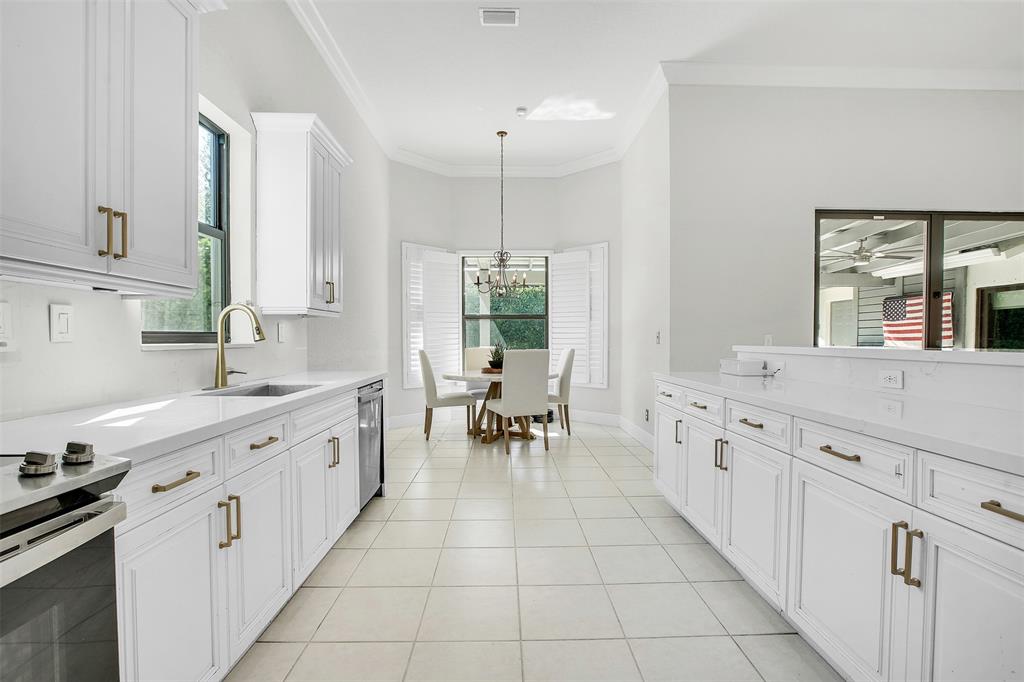 a large white kitchen with granite countertop a sink and dishwasher a stove top oven with wooden floor