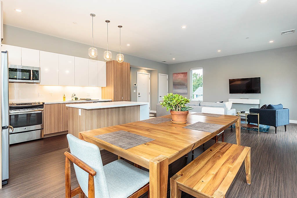 17 Ash Street Waltham, MA 02453 - Photo 16 of 32 a kitchen with granite countertop a stove a sink dishwasher a dining table and chairs with wooden floor