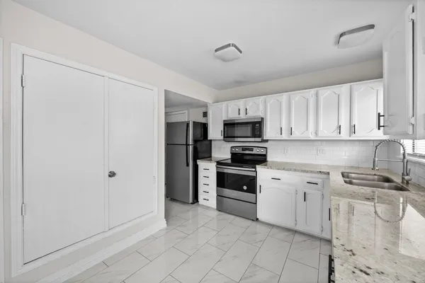 a kitchen with white cabinets and stainless steel appliances