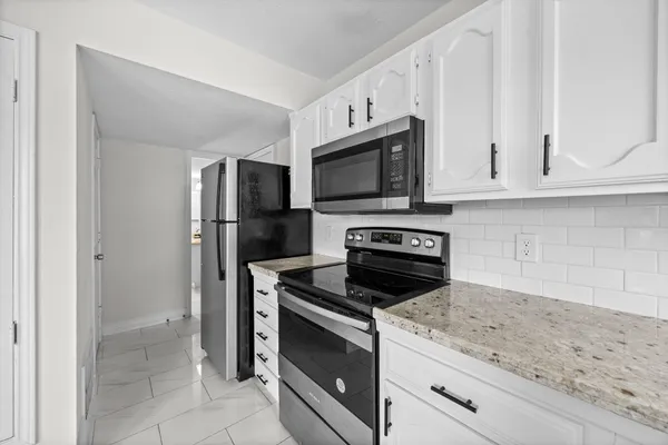 a kitchen with granite countertop white cabinets and stainless steel appliances