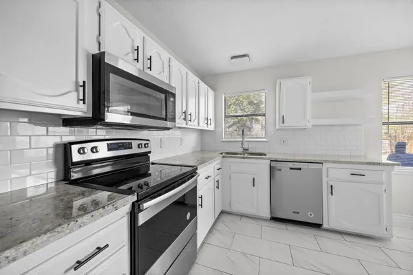 a kitchen with granite countertop cabinets stainless steel appliances and a counter space