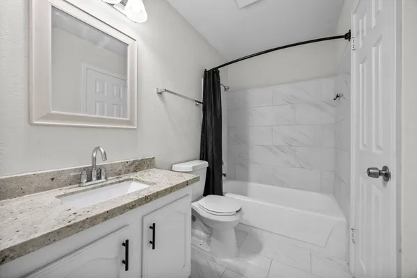 a bathroom with a granite countertop sink a toilet and shower