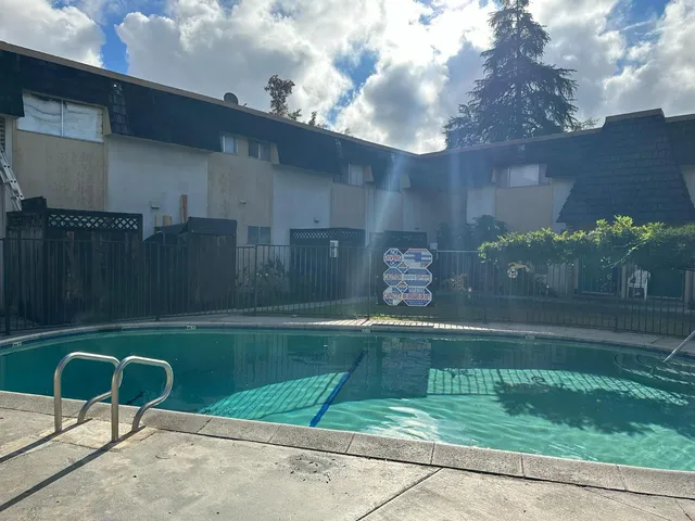 a backyard of a house with table and chairs plants with wooden fence