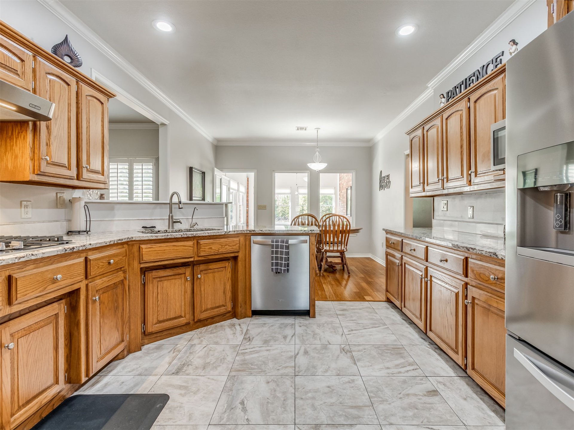 119 Mainsail Road Stigler, OK 74462 - Photo 13 of 52 Kitchen featuring wood cabinetry, light-toned granite countertops, a stainless steel gas range, and a stainless steel dishwasher
