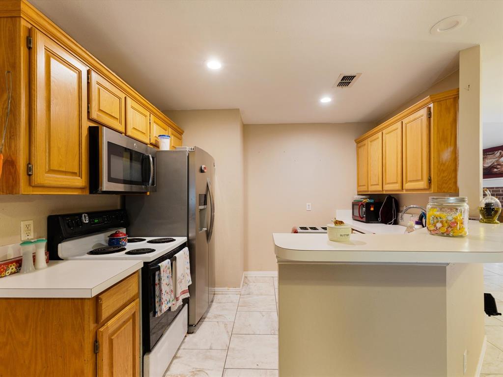 207 Quail Run Aubrey, TX 76227 - Photo 12 of 30 Kitchen featuring electric range oven, light countertops, stainless steel microwave, a peninsula, and recessed lighting