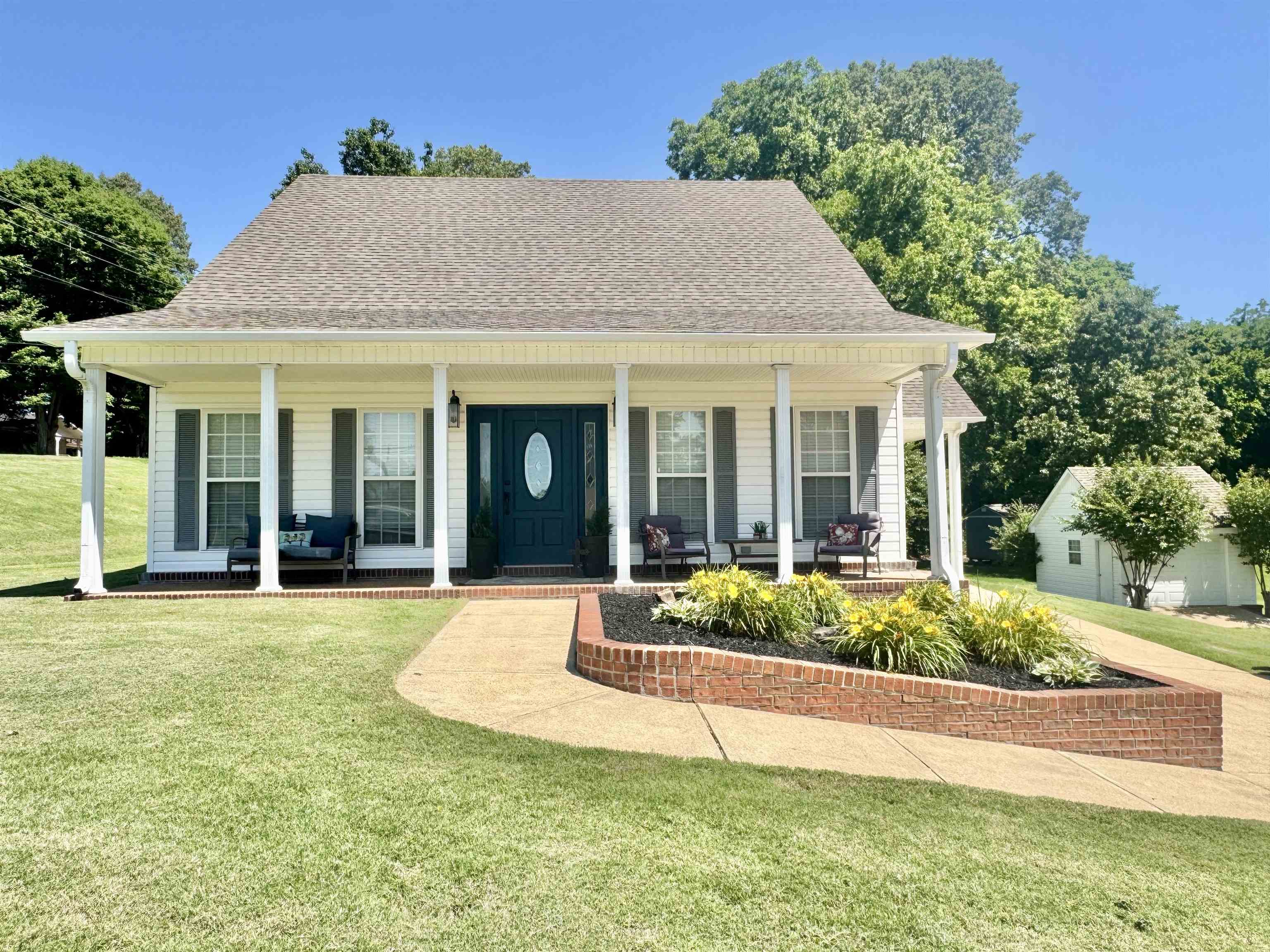 View of front facade featuring covered porch, a front lawn, and roof with shingles