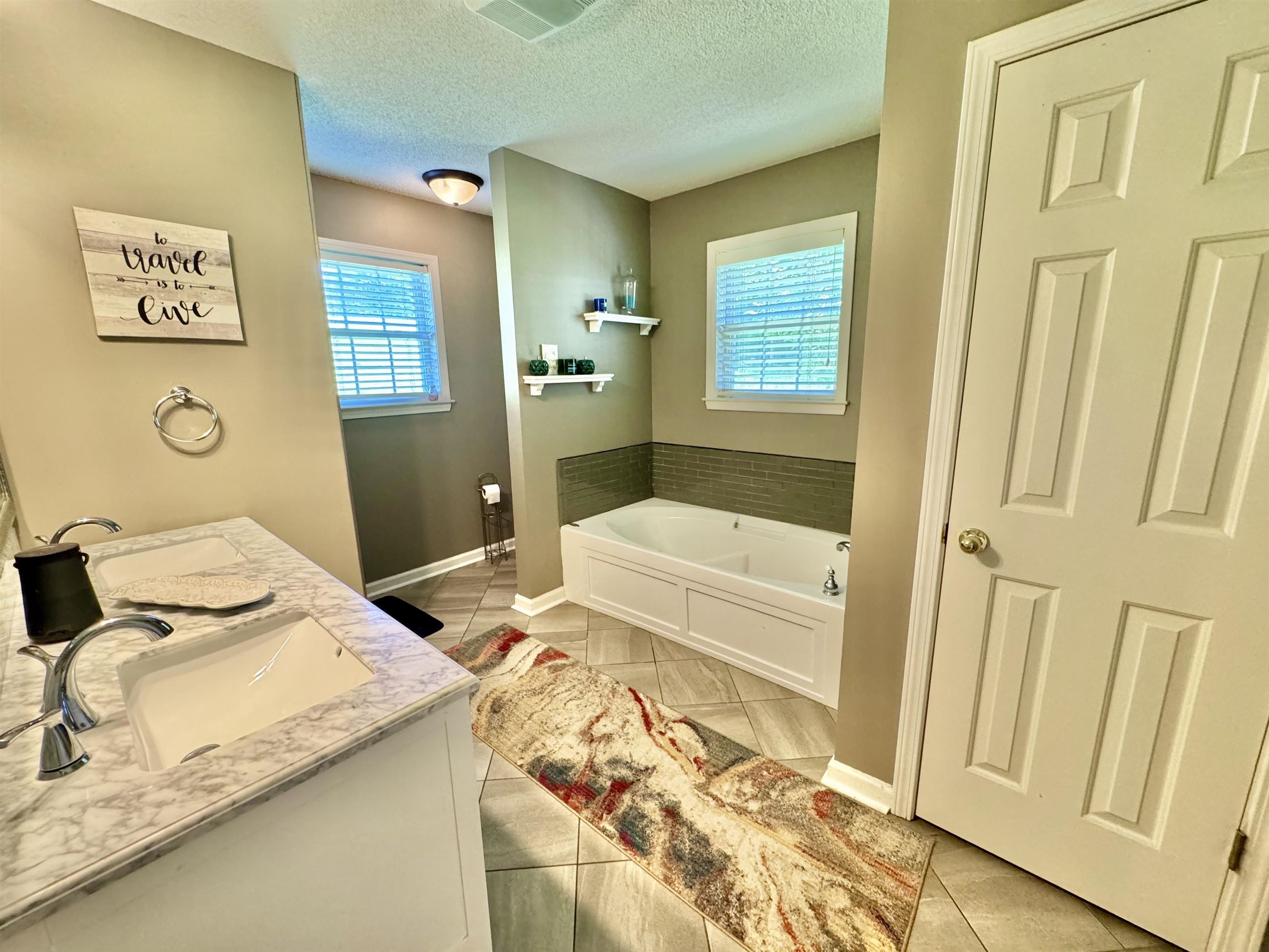 150 Westwood Circle Ripley, TN 38063 - Photo 13 of 28 Bathroom with a bath, tile patterned floors, double vanity, baseboards, and a textured ceiling