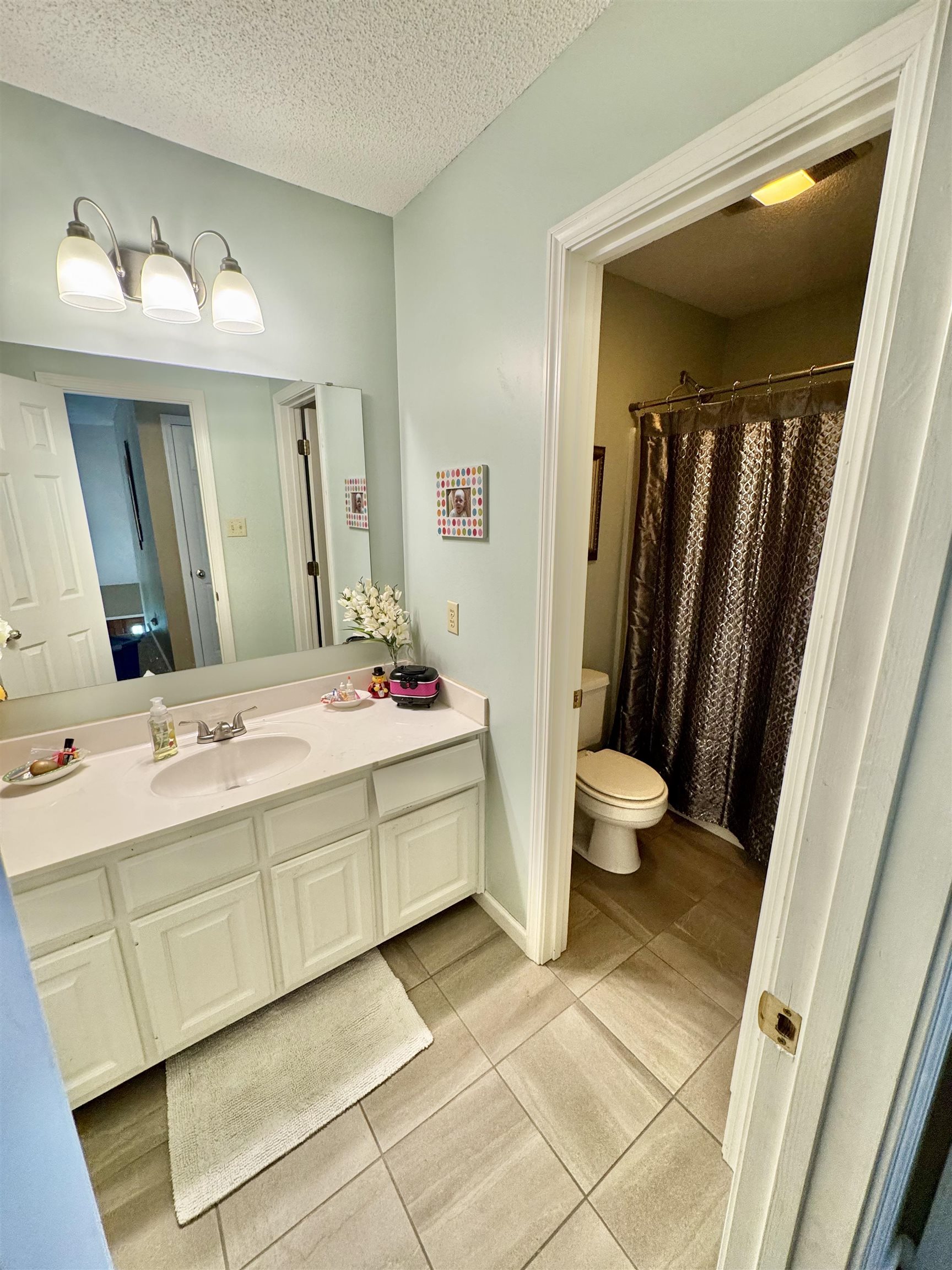 150 Westwood Circle Ripley, TN 38063 - Photo 16 of 28 Bathroom featuring toilet, vanity, tile patterned floors, a shower with shower curtain, and a textured ceiling