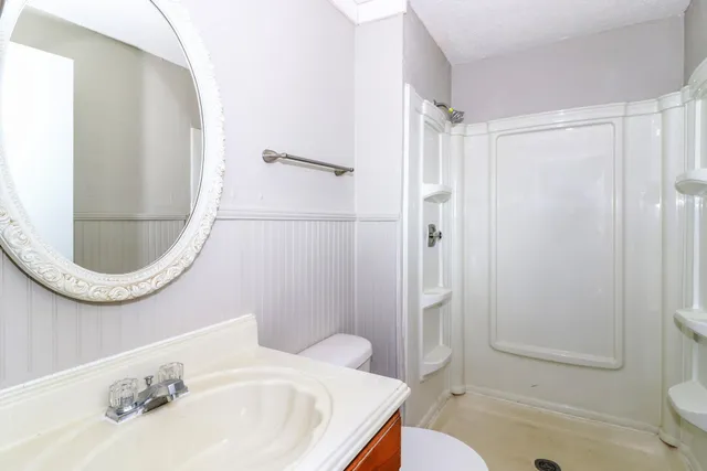 a bathroom with a sink a toilet and shower