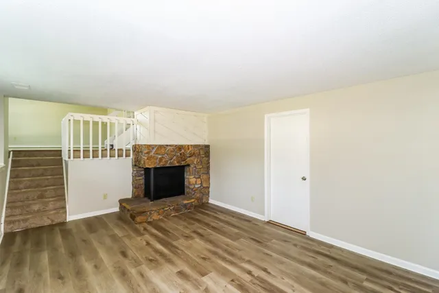 a view of empty room with fireplace and wooden floor