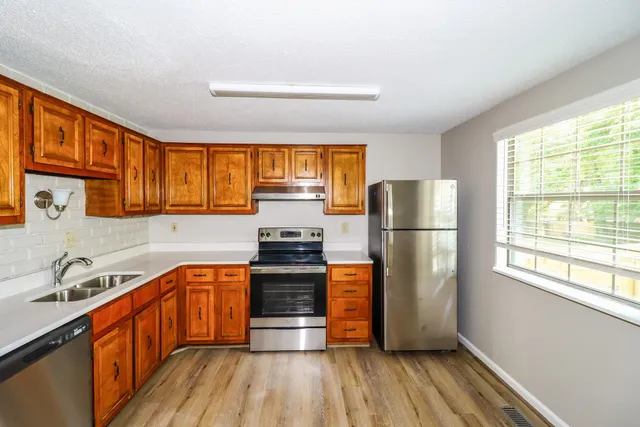 a kitchen with stainless steel appliances a refrigerator sink and wooden floor