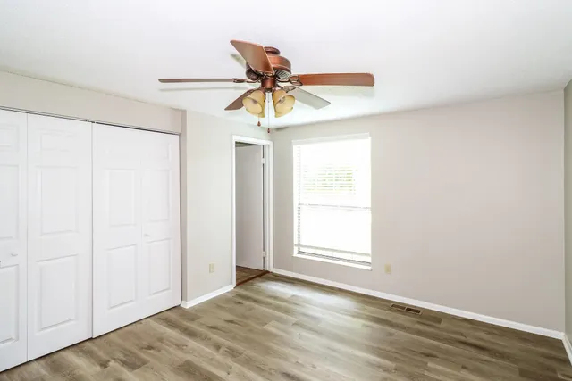 a view of empty room with wooden floor and ceiling fan