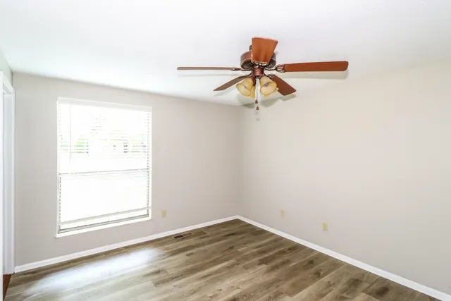 an empty room with a window and a fan