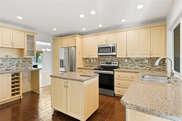 a kitchen with kitchen island granite countertop white cabinets and stainless steel appliances