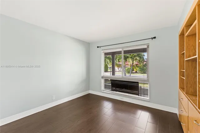 a view of an empty room with wooden floor and cabinet