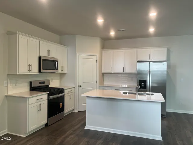 a kitchen with kitchen island granite countertop a sink cabinets and stainless steel appliances