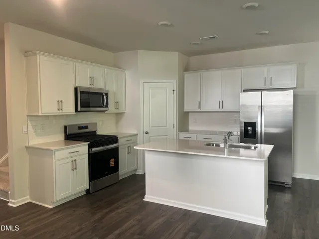a kitchen with stainless steel appliances granite countertop a sink stove microwave and refrigerator