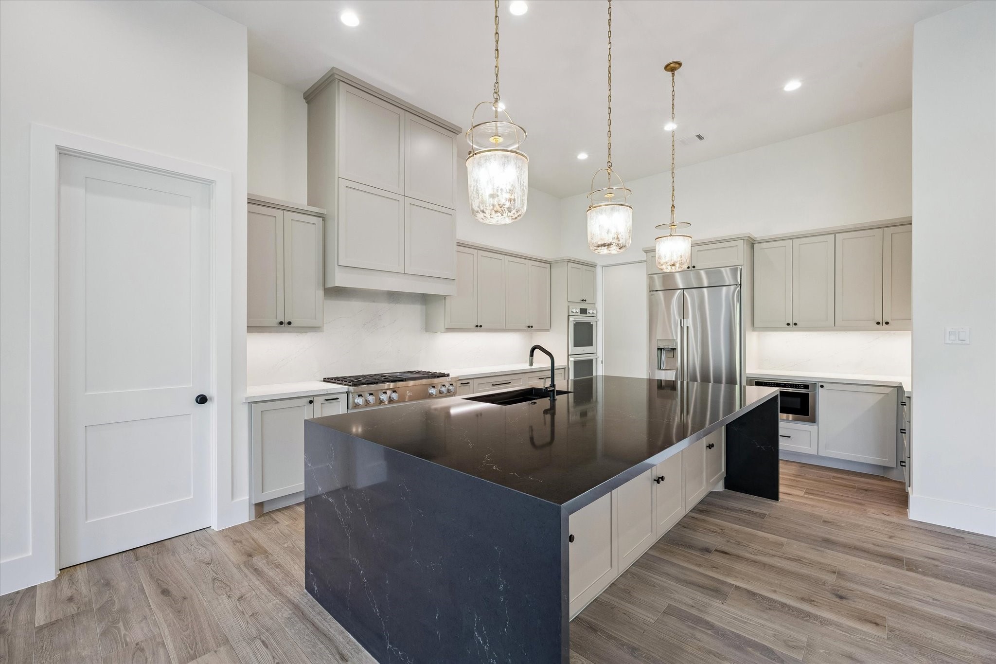 65 Shadow Creek Ridge Drive Spring, TX 77389 - Photo 13 of 41 Soft toned shaker cabinetry stretches to the ceiling for a clean, custom look, while under-cabinet lighting and a full-height backsplash keep things bright and polished.