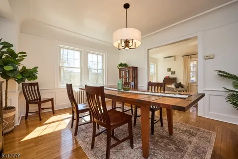 a dining room with wooden floor a chandelier a wooden table and chairs
