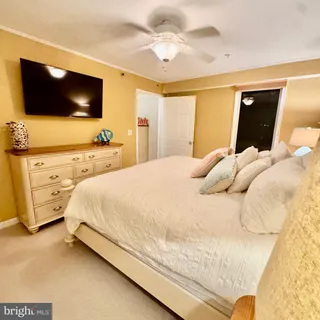 a bedroom with a bed and a flat tv screen on dresser