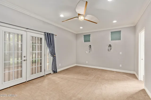 an empty room with chandelier fan and windows