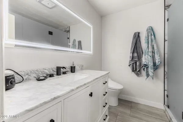 a bathroom with a sink and mirror with toilet