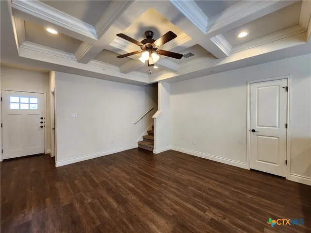 a view of an empty room with wooden floor and a ceiling fan